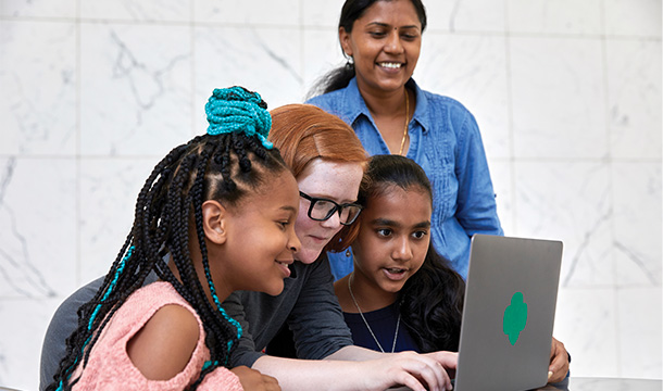 girl scouts and adults looking at a laptop