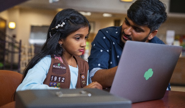 a male volunteer and a girl scout in front of a laptop