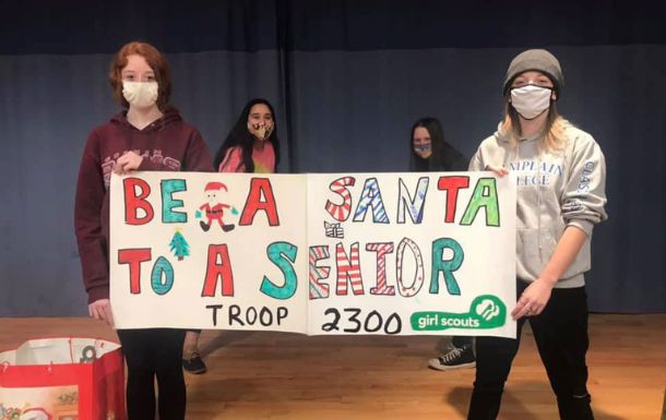 Girls from troop 2300 holding up a Be a Santa to a Senior sign