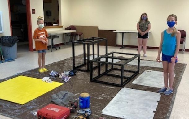 Girl Scouts from troop 507 surrounded by the parts of the cart they will be assembling