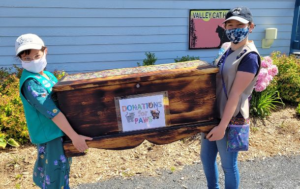 Two Girl Scouts from troop 83 carrying a donation box