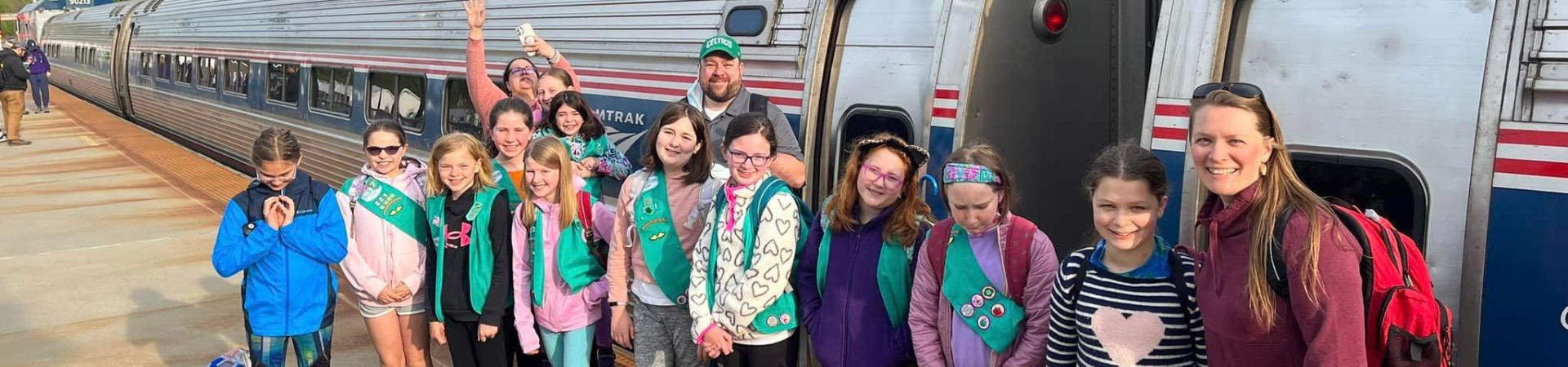  Girl Scouts and adults in front of the train that will bring them to Boston 
