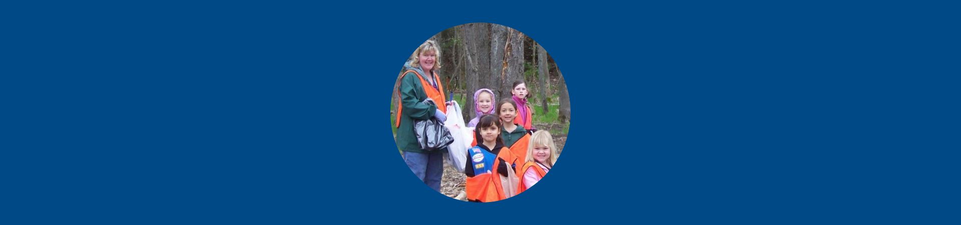  Leslie and a group of Daisy Girl Scouts picking up trash in the woods 