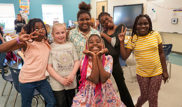 group of six girl scouts in a classroom posing for the camera
