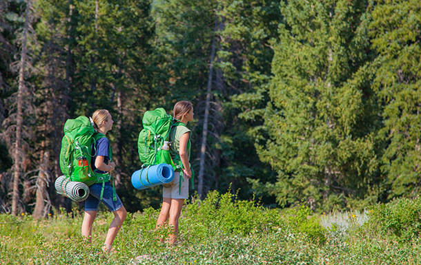 Girls standing in a field wearing hiking backpacks