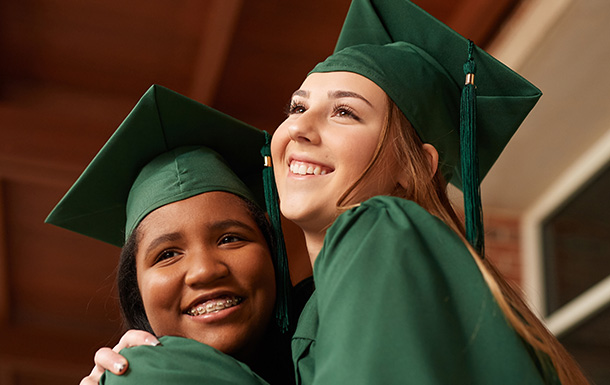 Two girls hugging in graduation caps and gowns