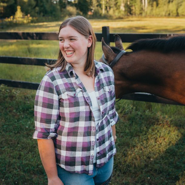 Picture of Abigail smiling and standing next to a horse