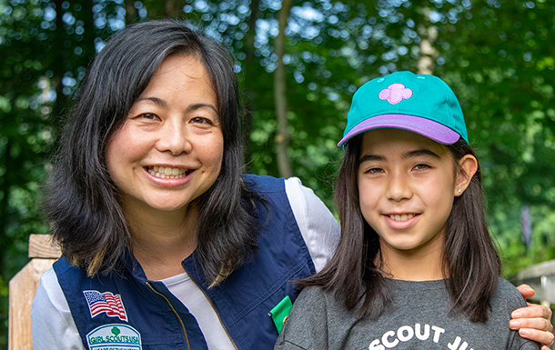 group of young girl scout daisies hiking with adult volunteer