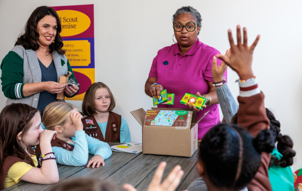 group of girl scouts with volunteers and brownie box