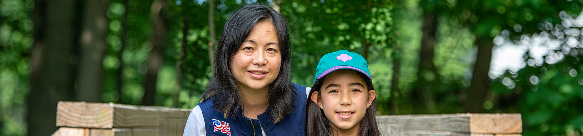  A volunteer and girl in Girl Scout gear smiling 